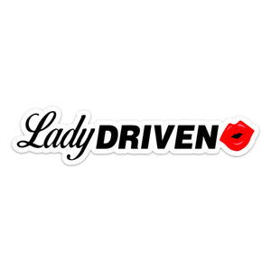 A bumper sticker design with the phrase 'Lady Driven' printed in bold black letters with a red lip mark at the end.
