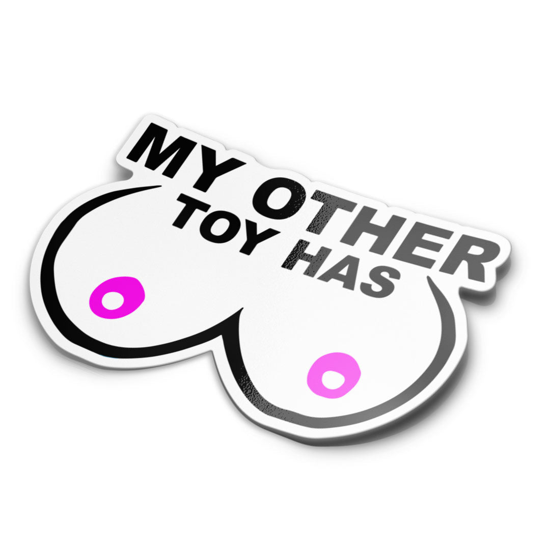 This image features a sticker with a bold, humorous design. The sticker is designed with a pair of breast-like shapes in white, outlined with black, and has pink nipples. Text says 'my other toy has'