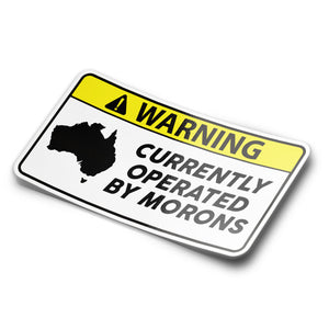 A sticker with a black and yellow warning sign that says 'WARNING CURRENTLY OPERATED BY MORONS' with a silhouette of Australia on it.