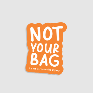 Sticker with 'Not Your Bag' text on a orange background. Designed to go on suitcases.
